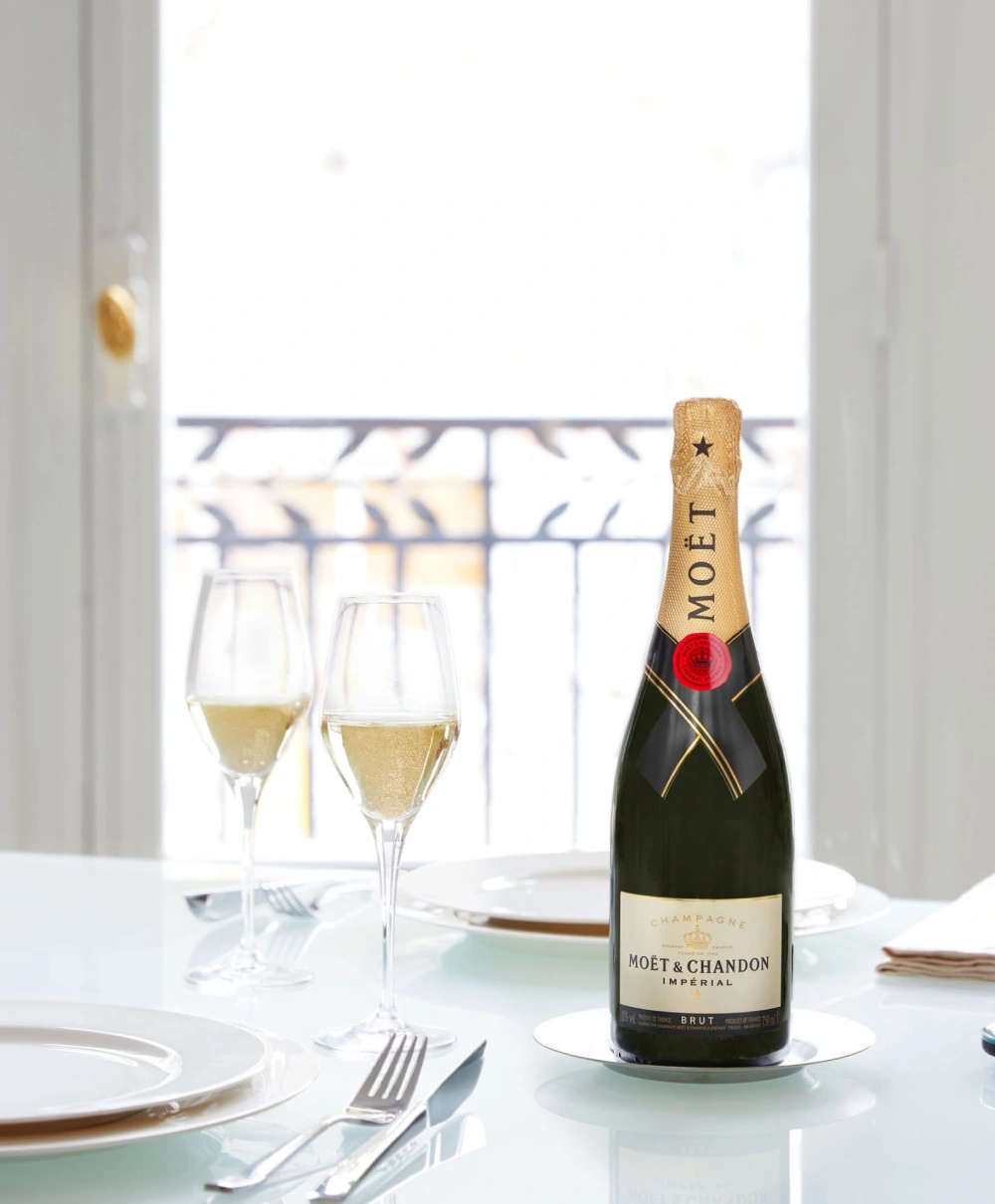 Moët & Chandon Brut Impérial champagne bottle with two filled champagne glasses on table