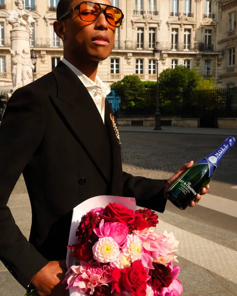 Pharrell Williams with a bottle of Moët & Chandon Limited Edition champagne and flowers